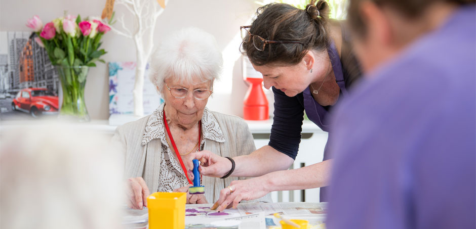 A resident enjoying arts and crafts with a member of staff