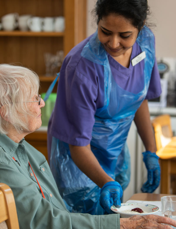 A member of staff serving a home-cooked meal to a resident
