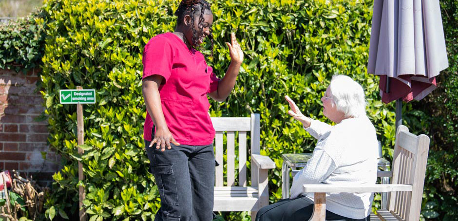 A carer and resident sharing a laugh in the garden